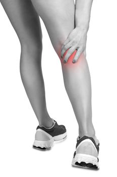 Female jogger with pain in her lower leg, black and white, isolated in white, red spot around painfull area