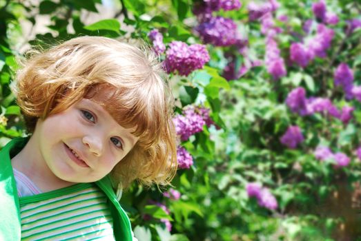Springtime scene with little girl in lilac garden