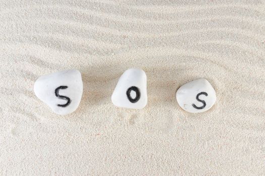 SOS word on group of stones with sand background