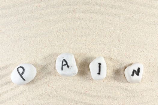 Pain word on group of stones with sand background