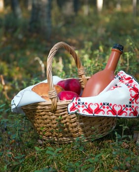 Picnic wicker basket with patty, food and wine bottle in wheat field 