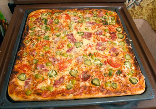 big pizza ham and vegetable on baking sheet 
