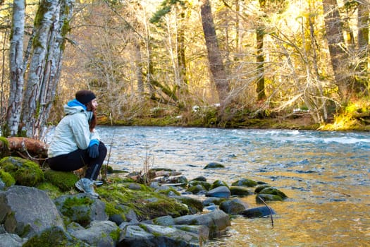 A female hiker takes a rest and looks out over the water of the McKenzie River in Oregon.