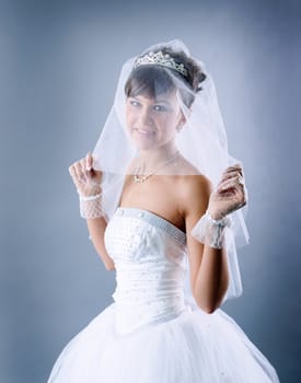 Beauty young bride dressed in elegance white wedding dress  gray studio background 