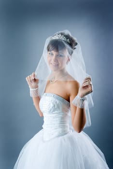 Beauty young bride dressed in elegance white wedding dress  gray studio background 