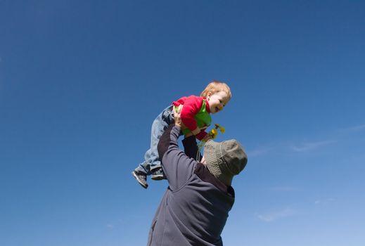 Father holding  little daughter.standing on green field 

