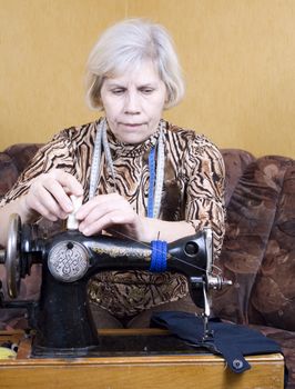 Senior woman using sewing machine at home
