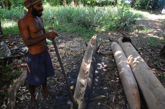 Man making canoe from wood in village, Papua New Guinea