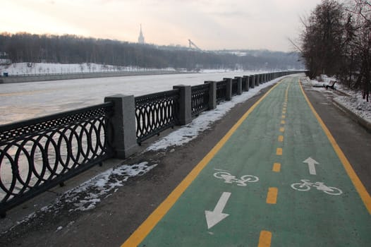 Green bicycle path at winter riverside road, Moscow, Russian Federation