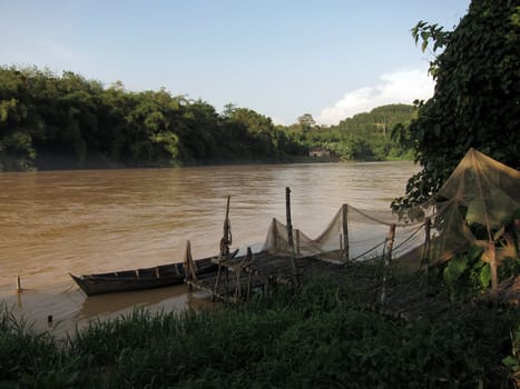 Boat and timber pier at muddy river, near Padang Tungku, Malaysia