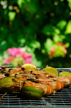 shrimps on barbecue with a garden in the background