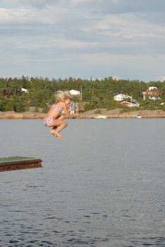Girl jumping in water a Norwegian summer day. Please note: No negative use allowed