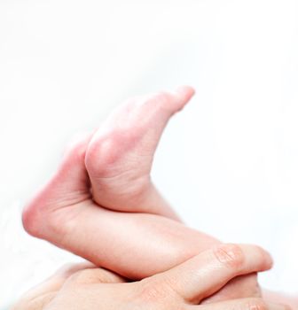 Mother holding a tiny baby's legs and feet in her hands, closeup cropped image on a white background