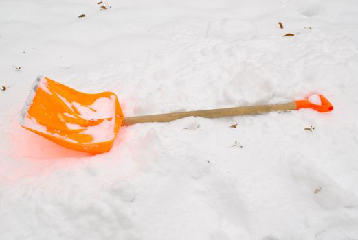 orange plastic snow clean tool lie rest on snowdrift in winter.