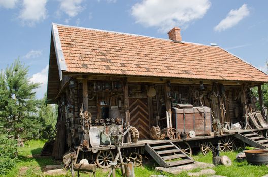 various different retro rural tools near old wooden log house.