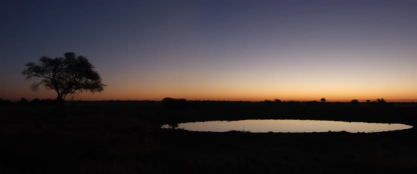 Panorama from two photos. Sunset view of the waterhole, Okaukeujo Rest Camp,  Etosha National Park, Namibia