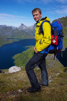 Young active man with backpack hiking on beautiful Lofoten islands in Norway on sunny day