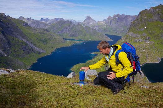 Young active man with backpack hiking on Lofoten islands in Norway on sunny day