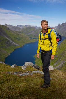 Young active man with backpack hiking on Lofoten islands in Norway on sunny day