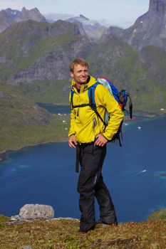 Young active man with backpack hiking on Lofoten islands in Norway on sunny day