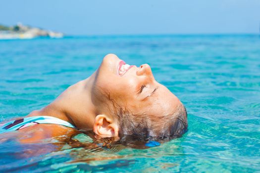 Closeup portrait of young girl swimming in the transparent sea