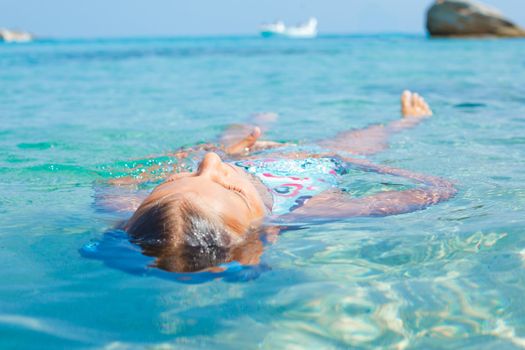 Closeup portrait of young girl swimming in the transparent sea