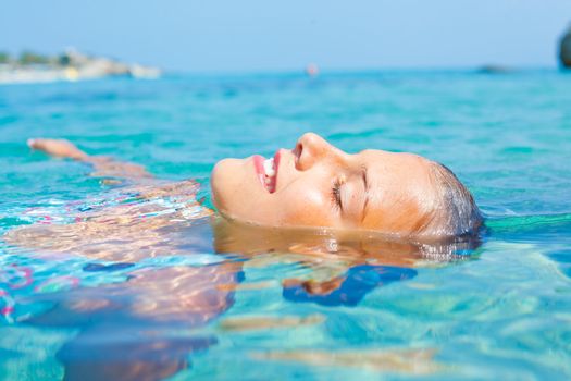 Closeup portrait of young girl swimming in the transparent sea