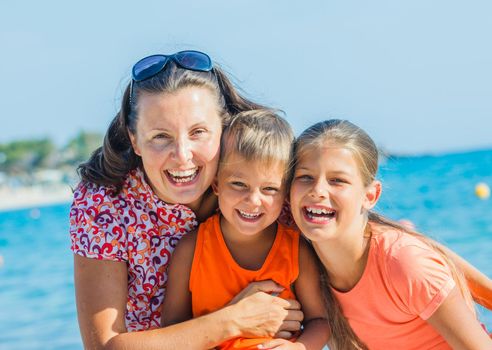 Portrait of happy family laughing and looking at camera on the beach