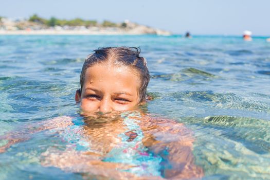 Closeup portrait of young girl swimming in the transparent sea