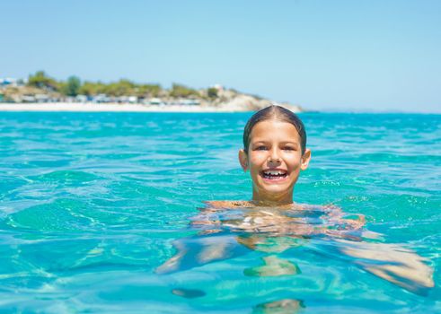 Closeup portrait of young girl swimming in the transparent sea