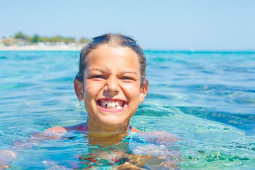 Closeup portrait of young girl swimming in the transparent sea