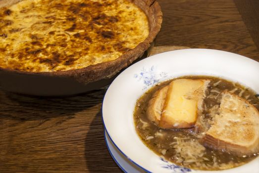 Homemade onion soup plate and quiche pie closeup