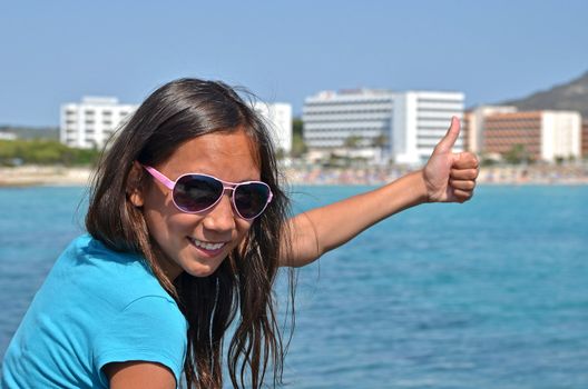 A young girl gives the thumb up for vacation in Mallorca, Spain