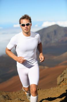 Good-looking athletic young man running cross-country through mountainous terrain training for a sports event