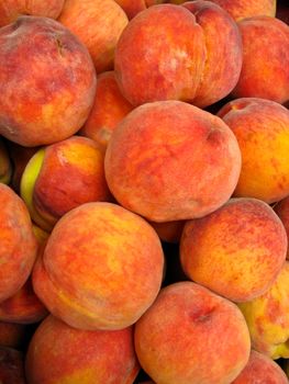 Many bright tasty peaches laying in the market