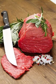 Raw beef on wooden table with rosemary ,sage and salt