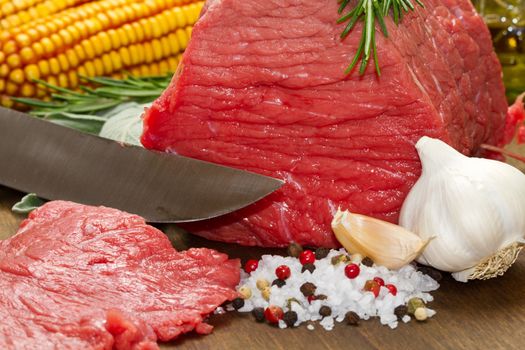 Raw beef on wooden table with rosemary ,sage , salt, cob and garlic