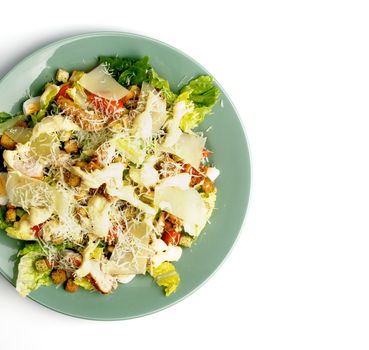 Caesar Salad with Grilled Chicken, Crouton, Romaine Lettuce, Sauce and Grated Parmesan Cheese closeup on Green Plate. Top View