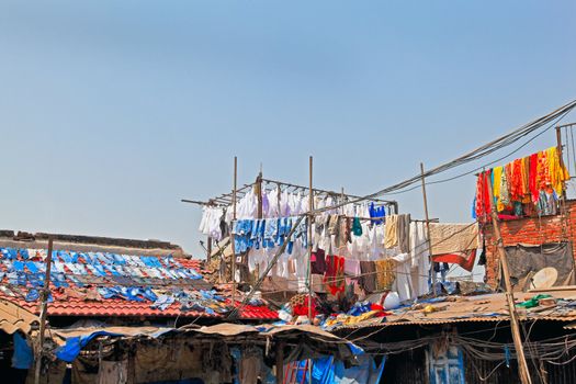 Denim drying on slate roofs and clothes in hand made bamboo racks at commercial laundry in Bombay India