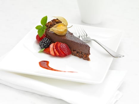 chocolate cake with strawberry and mint on a white plate