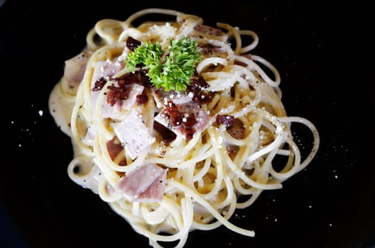 Spaghetti with ham isolated in black plate