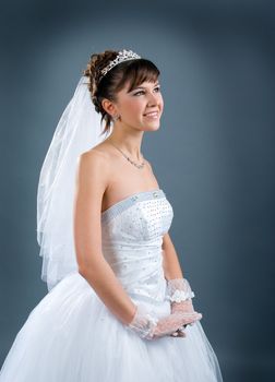 Beauty young bride dressed in elegance white wedding dress  gray studio background 