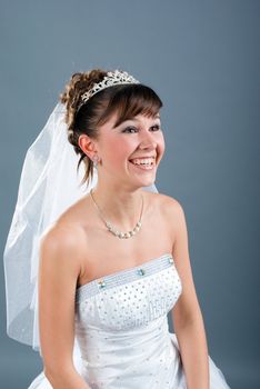 Beauty young bride dressed in elegance white wedding dress  gray studio background 