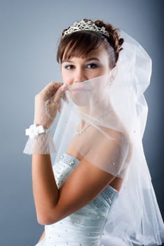 Beauty young bride dressed in elegance white wedding dress  gray studio background 