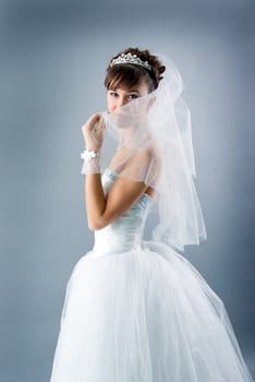 Beauty young bride dressed in elegance white wedding dress  gray studio background 