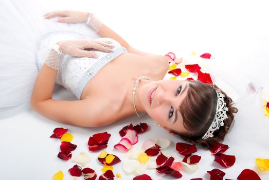 Beautiful sexy bride on  floor among red rose petals on white background 
