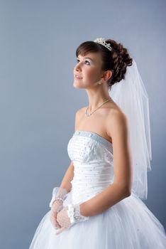 Beauty young bride dressed in elegance white wedding dress  gray studio background 