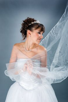 Beauty young bride dressed in elegance white wedding dress  gray studio background 