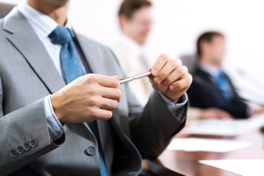 businessman sitting at a table and holding a pen