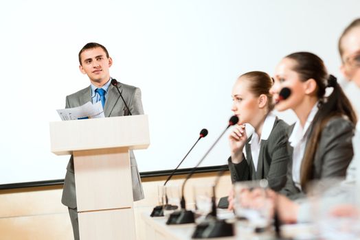 businessmen communicate at the conference, sitting at the table, on the table microphones and documents